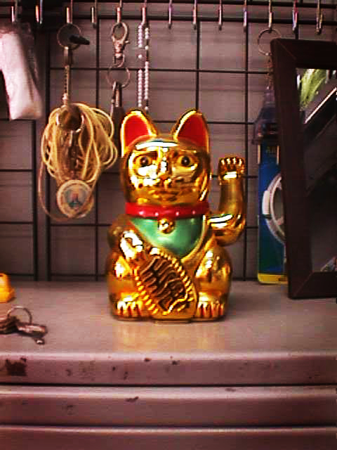 A golden maneki-neko sitting on top of a metal shelf