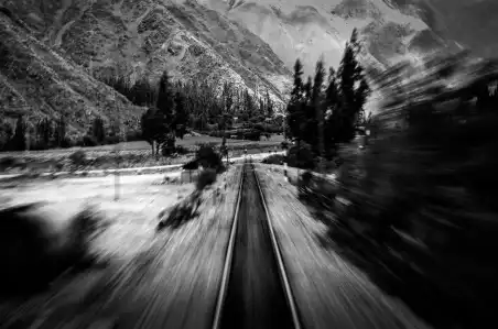 A black and white photograph of a train track drifting through a mountainous region